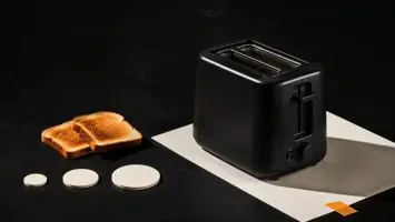 Enkel svart brødrister med ristede skiver og tre umerkede sammenligningsbrikker
